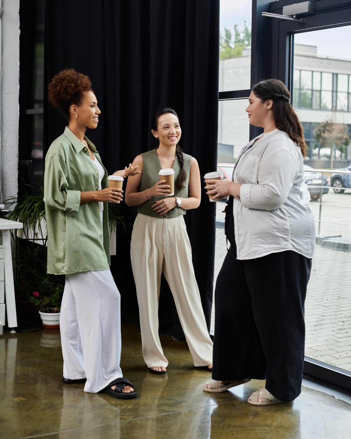 Tre medarbeidere står i samtale med kaffe i et lyst rom.